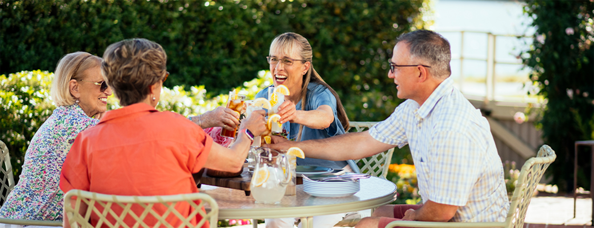 Image of middle aged people toasting at a table outdoors